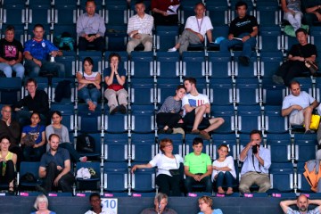 Spectators watch a mixed doubles match between Britain and China in a sparsely-populated stadium during badminton at the 2012 Summer Olympics, July 31, 2012.