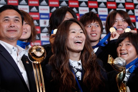 Japan's women's World Cup soccer team head coach Sasaki and players pose during a photo session after a news conference in Tokyo