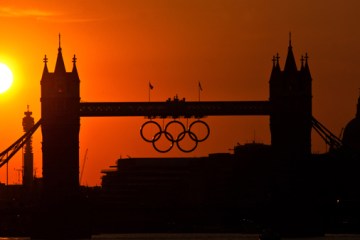 image: The sun sets behind the 2012 London Olympic Rings on Tower Bridge in London, on August 10, 2012.